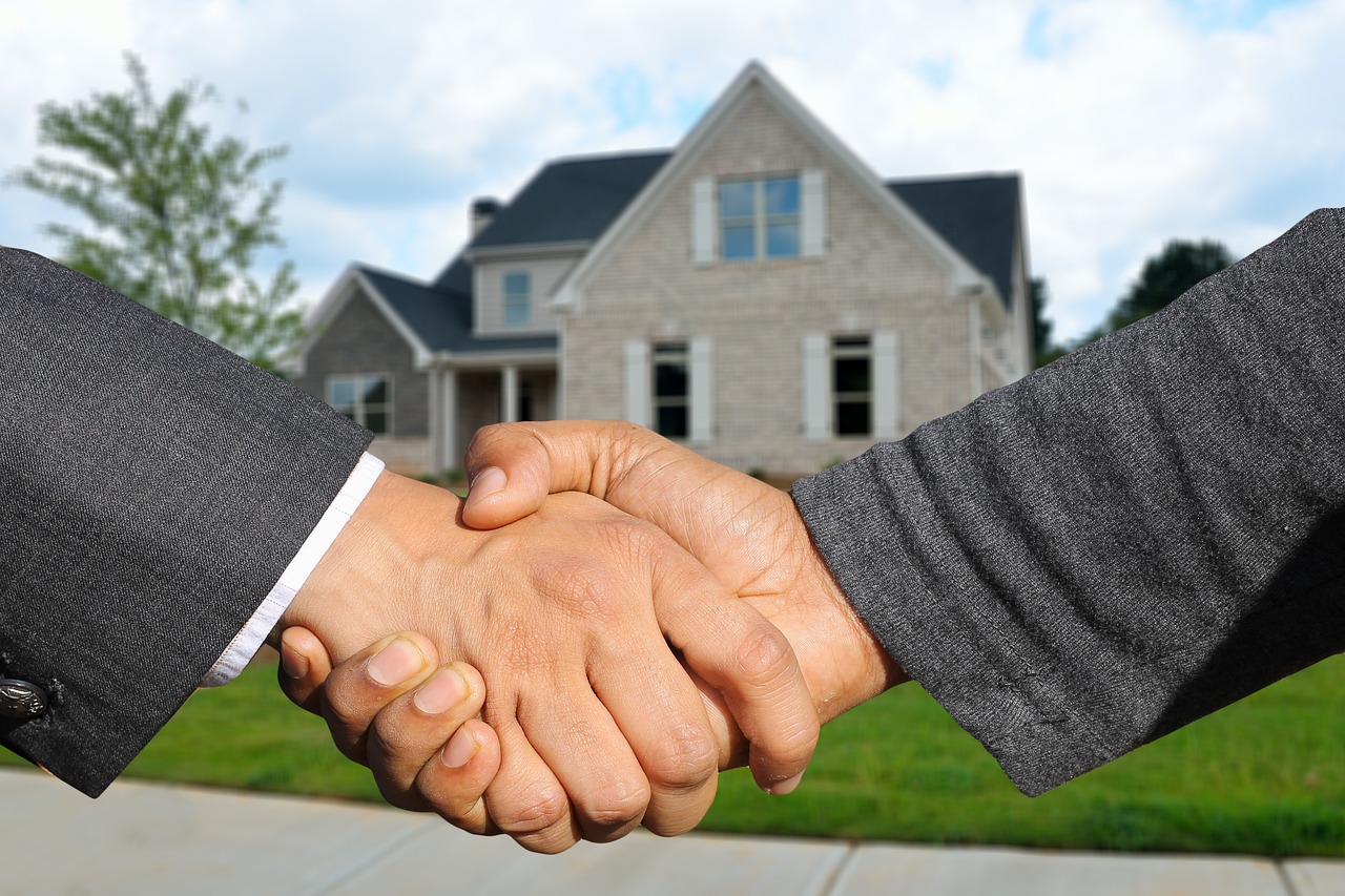 Property manager shaking hands with a new resident in front of a home